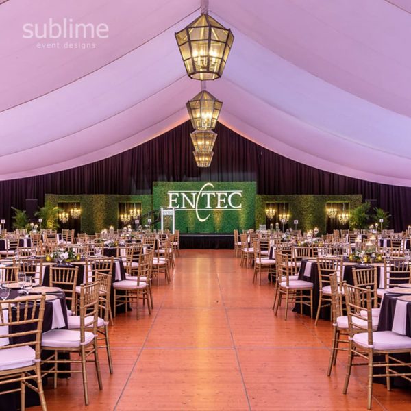 Holiday event decor with chandeliers and foliage walll
